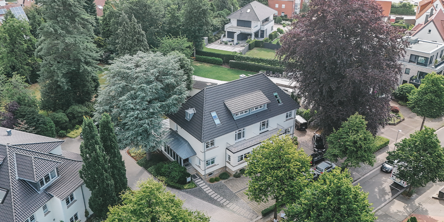 Drohnenaufnahme eines modernen Wohnhauses mit Garten und umliegender Nachbarschaft